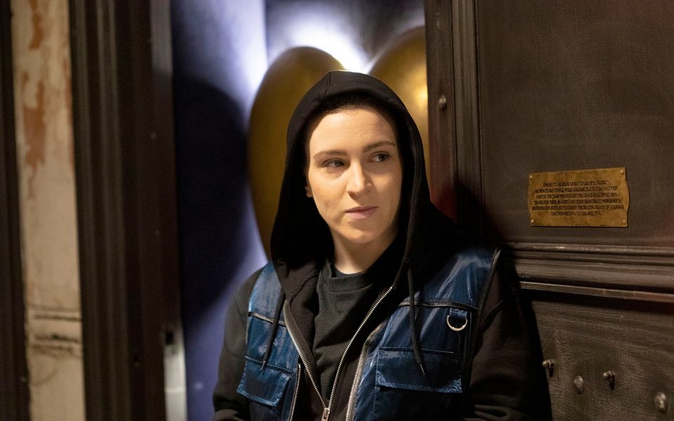 An image of a person wearing a black hoodie leant against the door to our bronze heart installation.