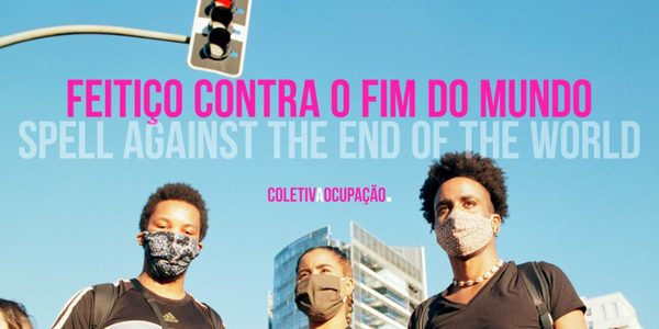 Feitico contra o fim do mundo (pink text), translated as Spell Against The End Of The World (grey text), on a blue sky background. Three people wearing fabric facemasks look down to the camera, with a traffic light and skyscraper visible in the background