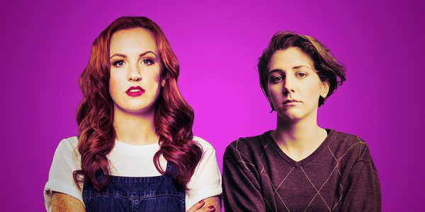 Two white women look ahead at the camera, against a purple background.