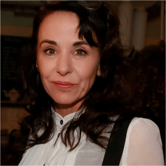 A white woman with long dark hair wearing a white shirt