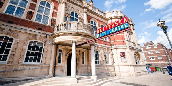 The front of our building, a Victorian town hall made from pale stone and red brick. The Battersea Arts Centre sign is extended from the entrance in red and blue with yellow lettering.