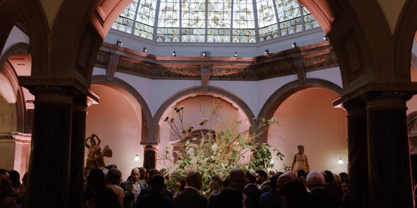 A crowd of people in the octagonal hall with a large flower arrangement in the middle.