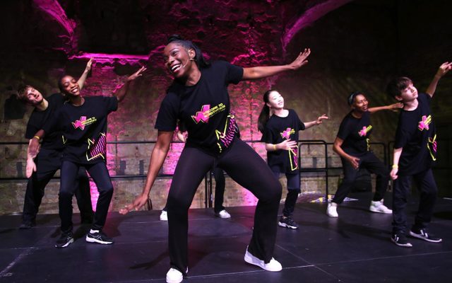 Performers dance energetically, arms spread out.