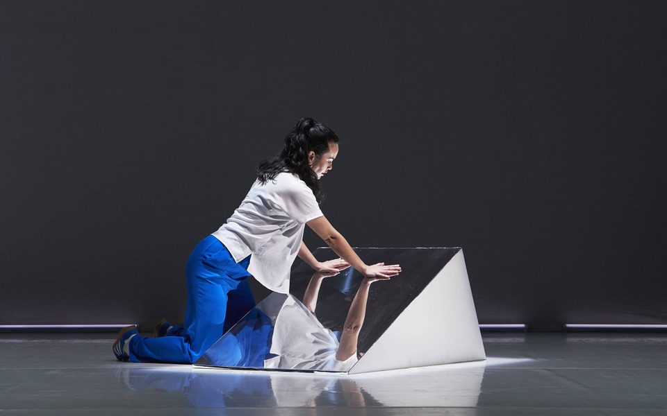 Rinse © Zan Wimberley A woman in a white shirt and blue trousers is kneeling with her hands placed on a mirror.
