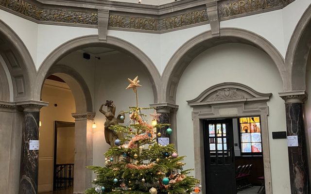 BAC’s Octagonal Hall with a very merry Christmas tree in the centre of it, complete with tinsel, baubles and a gold star on top.